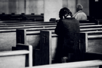 Zdjęcie przestawiające osobę modlącą się w kościele
